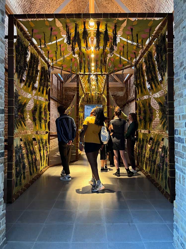 Tabita Rezaire, architect Yussef Agbo-Ola of Amakaba, and Olaniyi Studio, Ikum Drying Temple, 2022. Dyed cotton tensiles, reclaimed pine frame, medicinal plants, recycled cellulose cable ties. Installation view, Back to Earth exhibition at Serpentine North, 22 June – 18 September 2022. Photo: Veronica Simpson.