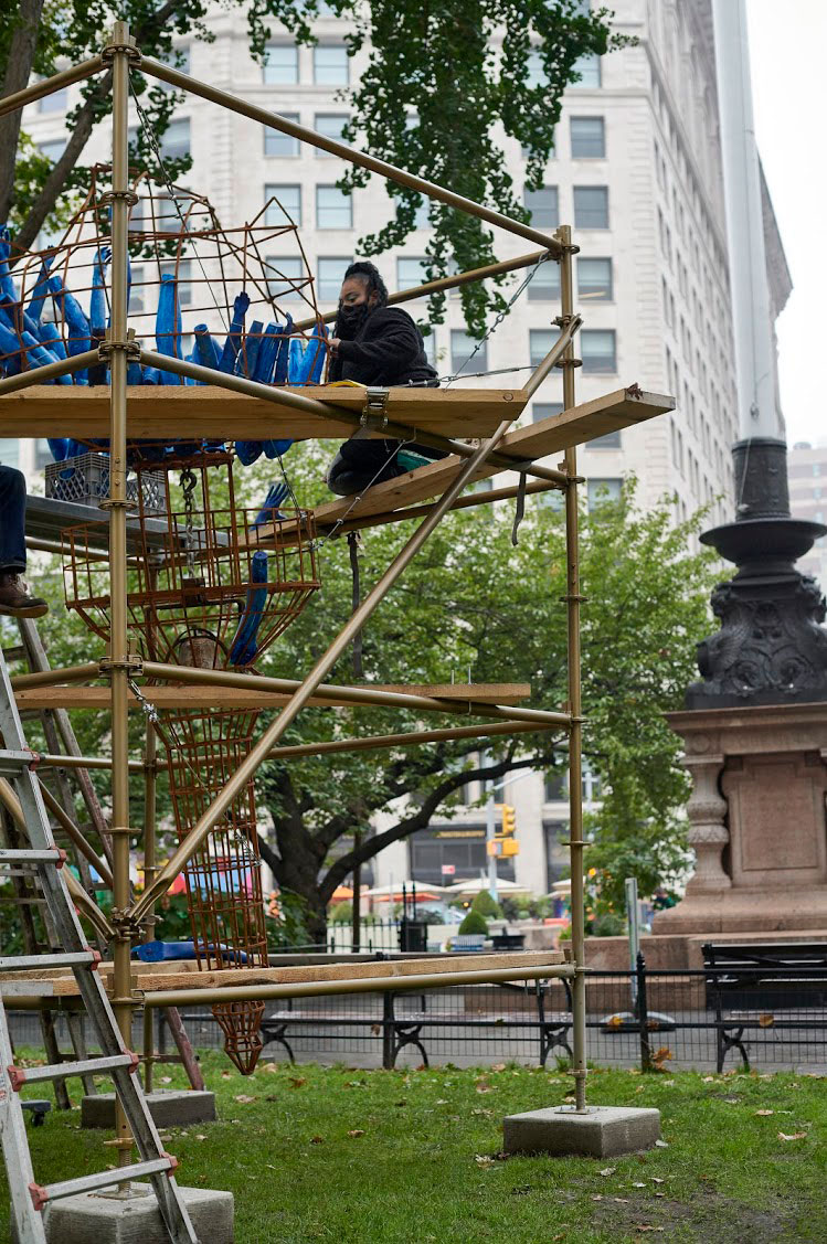 Abigail DeVille installing Light of Freedom in Madison Square Park, 2020. Welded steel, cabling, rusted metal bell, mannequin arms, metal scaffolding, wood, 156 x 96 x 96 inches approximately. Collection the artist. Madison Square Park Conservancy, New York. Photo: Andy Romer.