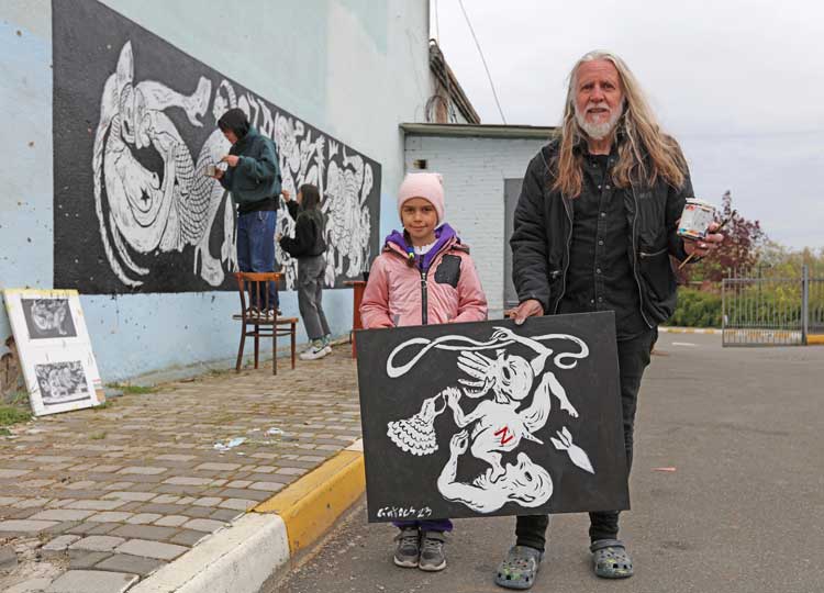 George Gittoes with Eva and Warhouse mural in progress, the Central House of Culture, Irpin. 2023. © the artist.