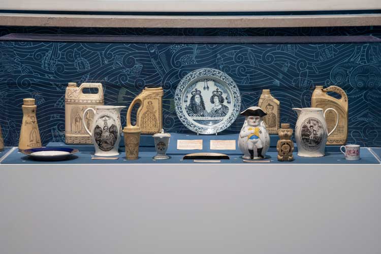 Political Pottery (selected items listed): Pitcher, c1805, unknown artist. Glazed earthenware, 23.8 × 22.4 × 10.2 cm. Brooklyn Museum; Bequest of Caroline Low and Charles T. Pierce. Photo: Brooklyn Museum; Right Pitcher, c1800, porcelain, enamel, gilding. Brooklyn Museum; H. Randolph Lever Fund; Plate, Netherlands, c1690, glazed earthenware, 34 cm, Brooklyn Museum, Museum Collection Fund; Napoleon Jug, 1895, porcelain, belleek ware. 24.8 x 11.4 cm, Brooklyn Museum, Bequest of Dr Marion Reilly; Various scrimshaw objects by Duke Riley: Painted salvage plastic, ink and wax. From Poly S. Tyrene Memorial Maritime Museum, 2019-22. Courtesy of the artist. Installation view at Brooklyn museum: Photo: Danny Perez.